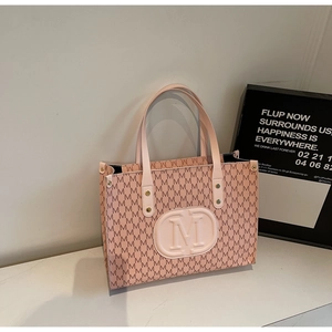 Detail of pink tote bag showing the embossed round M logo and letter printed pattern