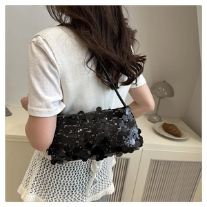 Detail of trendy black sequin shoulder bag with shimmering texture and slim strap