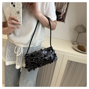 Close-up of black sequin baguette bag with adjustable leather strap in lifestyle setting