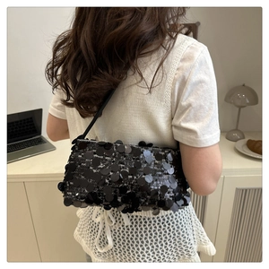 Detail of elegant black sequin handbag with chain strap showing shiny texture on shoulder