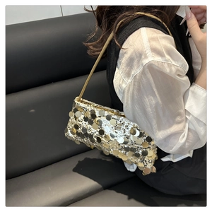 Close-up of sparkling gold paillettes and metallic tubular strap on evening bag