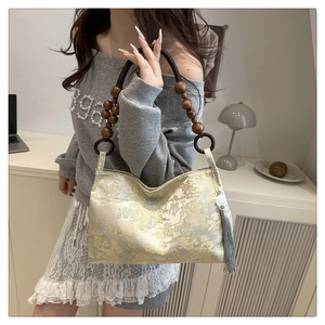 Detail of jacquard brocade bag featuring golden landscape patterns and wood bead handle