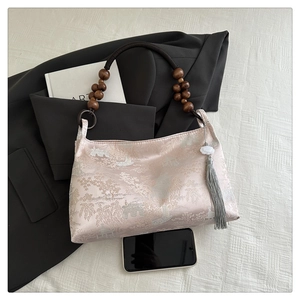 Detail of silk jacquard handbag with floral pattern and dark wood bead handle