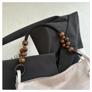 Detail of pink satin tote bag with traditional Chinese embroidery and wooden bead strap