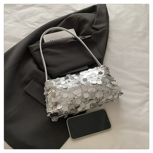 Detail of silver sequin handbag with round metallic discs on a black blazer background