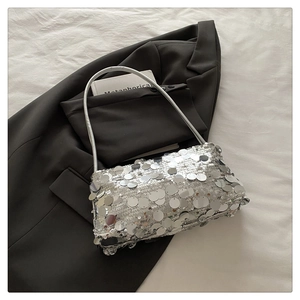 Detail of silver sequined handbag featuring a rectangular structure and sleek metal handle