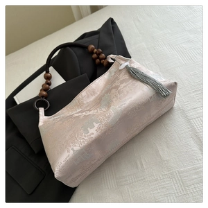 Close-up of pink jacquard handbag featuring traditional landscape patterns and wood bead handle