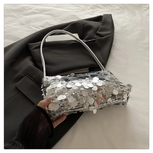 Detailed view of silver sequin handbag with chain strap on a black blazer background
