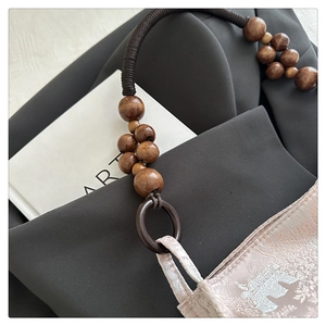 Detailed shot of wooden beads handle and pink jacquard fabric of a Chinese style handbag