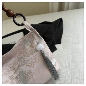 Detail of pink floral brocade fabric with wooden bead handle and silk tassel on handbag