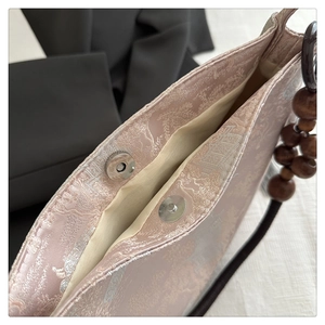 Macro shot of magnetic closure and embroidery details on the pink jacquard tote bag