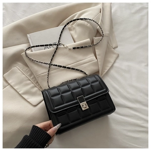 Detail of black quilted chain crossbody bag with silver square twist lock on a blazer