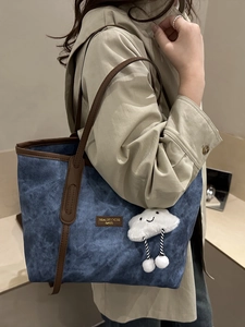 Large denim tote bag with brown leather trim and cute white cloud plush pendant