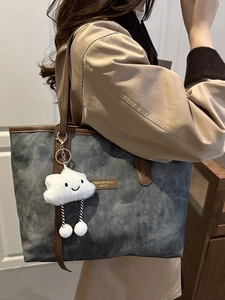 Gray-blue denim tote bag with brown leather straps and a cute cloud plush charm accessory