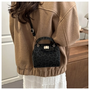 Detail of a chic leopard print crossbody bag with a gold square twist lock on a wool coat