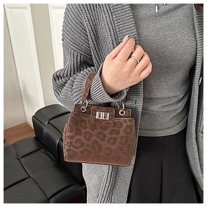 Close-up of leopard print mini handbag with metal ring handle and retro lock on black leather