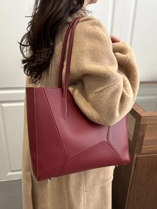 Deep red geometric patchwork tote bag shown with a camel wool coat in daily scene