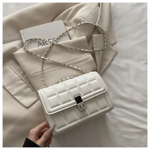 Close-up of white quilted crossbody bag with silver metal lock and chain strap detail