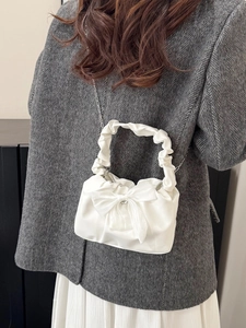 Sac bandoulière blanc à nœud avec détails plissés et chaîne porté par un modèle