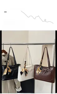 Detail of crocodile pattern tote bag with decorative silk scarf handle in three colors
