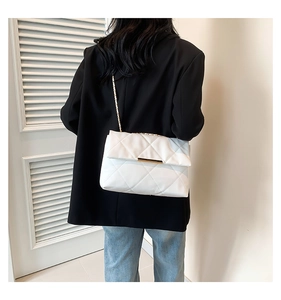 Detailed back view of white quilted crossbody bag with gold chain on black blazer
