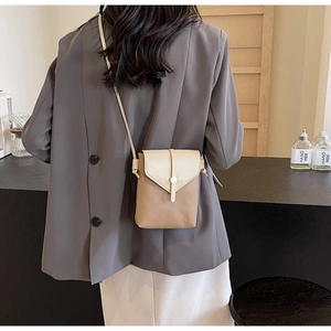 Detail showing two-tone beige and brown lychee grain leather phone bag with gold clasp