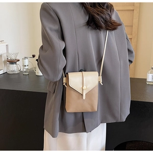 Close-up of a two-tone crossbody mini bag worn by a model in a casual setting