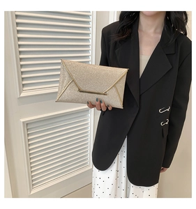 Detail van champagne goudkleurige enveloppe clutch met geweven textuur en metalen balk