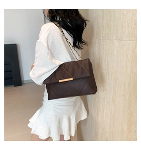 Detail of a dark brown quilted shoulder bag with gold chain strap and metal lock closure