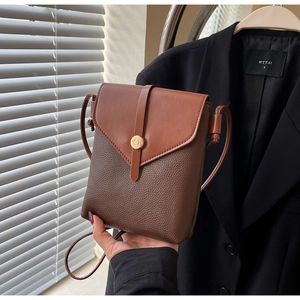 Detail of brown contrast leather crossbody bag with round gold metal buckle and hand strap
