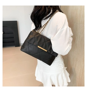 Detail of black quilted chain shoulder bag with elegant gold buckle and strap