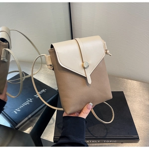 Detail of lychee textured leather crossbody phone bag with round golden metal buckle