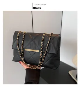 Detail of black quilted leather shoulder bag with gold chain strap and metal hardware