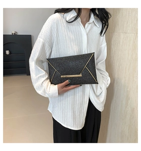Detail van de zwarte glitter enveloppe clutch met gouden bies en metalen decoratie