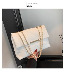 Detail of white quilted leather bag with gold metal chain and elegant bar closure