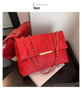 Close-up of red quilted shoulder bag with gold metal clasp and chain strap detail