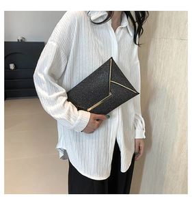 Detail van elegante zwarte pailletten enveloppe clutch met gouden V-vormige metalen gesp