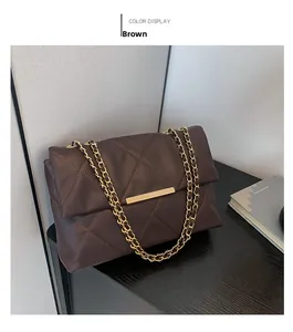 Detail of brown quilted shoulder bag with gold chain strap and metal lock closure