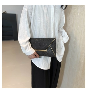 Detail van zwarte lovertjes envelop clutch met elegante goudkleurige metalen randversiering