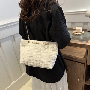 Elegant white checkered tweed tote bag with metal chain strap worn by a model