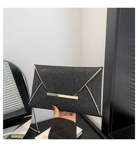 Detail van zwarte glitter enveloppe clutch met gouden metalen rand in de hand