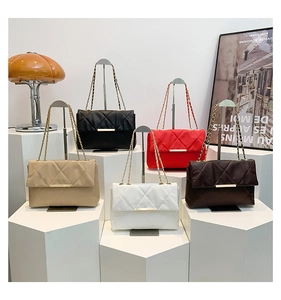 Five quilted chain crossbody bags in beige black red white and brown displayed on pedestals