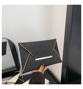 Macro-opname van zwarte glitter clutch tas met goudkleurige rand en metalen gesp