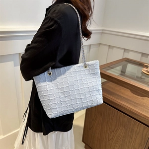 Elegant light blue tweed tote bag with gold chain strap shown in a lifestyle scene