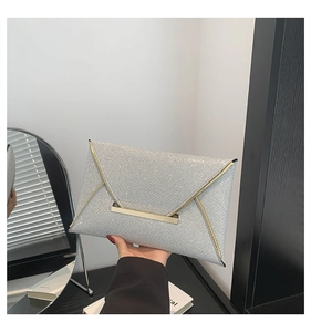 Glinsterende zilveren enveloppe clutch met gouden metalen rand in een stijlvolle setting