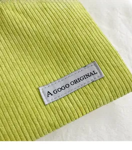 Détail du tissu en velours côtelé vert clair avec étiquette de marque et texture côtelée