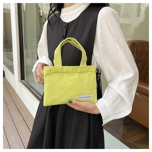 Détail du mini sac à main en velours côtelé vert avec texture et étiquette logo