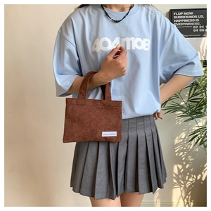 Détail d'un sac à main en velours côtelé marron avec texture et étiquette blanche
