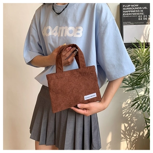 Détail d'un sac cabas en velours côtelé marron avec double poignée et étiquette rétro