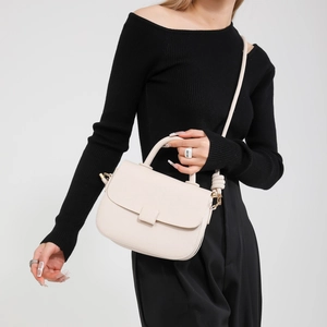 Beige pebble leather crossbody bag with top handle and adjustable strap worn by model